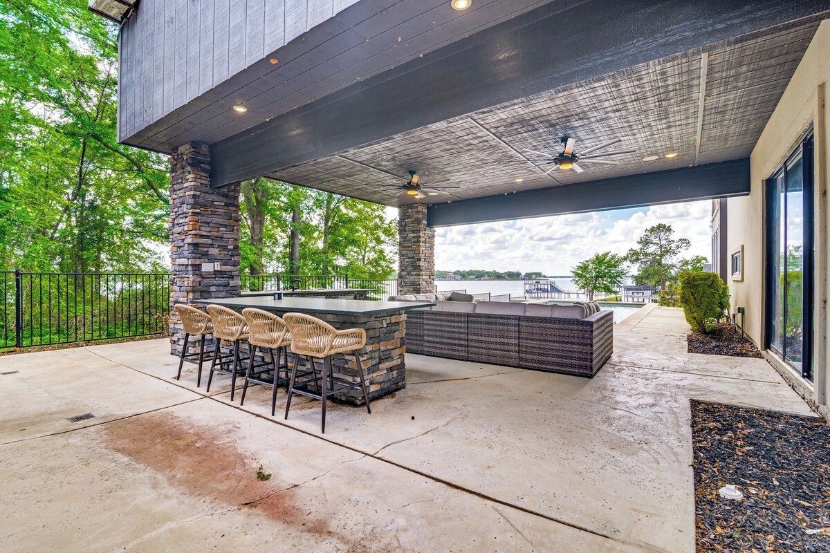 Un área de bar al aire libre con una columna de piedra, taburetes de bar y una zona de estar.