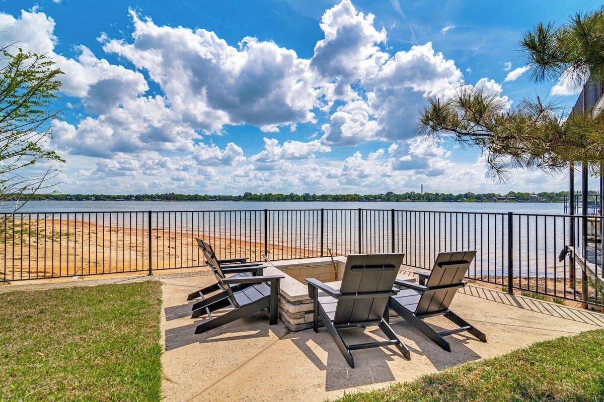 Un espace extérieur aménagé avec des chaises et une table, offrant une vue sur une étendue d’eau et une côte lointaine.