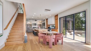 Een moderne keuken met een centraal eiland, een houten trap en grote schuifdeuren naar een terras.