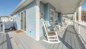 A covered porch with rocking chairs, a small table, and a potted plant. - 2 BR Bay Breeze Retreat (Lower Township)