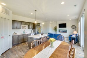 A modern kitchen with a central island, a dining area with a wooden table, and a living room with a blue sofa. - Updated Garden City Retreat <1 Mi to Bear Lake and walking distance to stores! (Garden City)