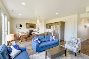 A modern living room with a blue sofa, a coffee table, and a patterned armchair. - Updated Garden City Retreat <1 Mi to Bear Lake and walking distance to stores! (Garden City)