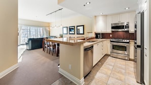 A modern kitchen with a central island, stainless steel appliances, and a dining area with a view.