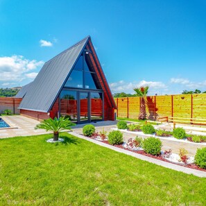 A modern house with a triangular roof, a swimming pool, and a well-maintained garden. - Hira Deluxe Bungalov (Ondokuzmayis)
