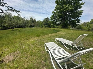 A grassy outdoor area with two white lounge chairs.