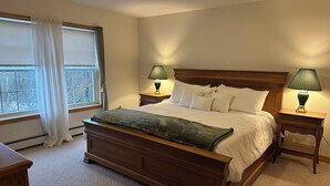 Una camera da letto con un letto in legno, due comodini con lampade, una finestra con tende e un termosifone.