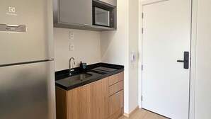 Una cocina compacta con refrigerador, microondas y armarios de madera.