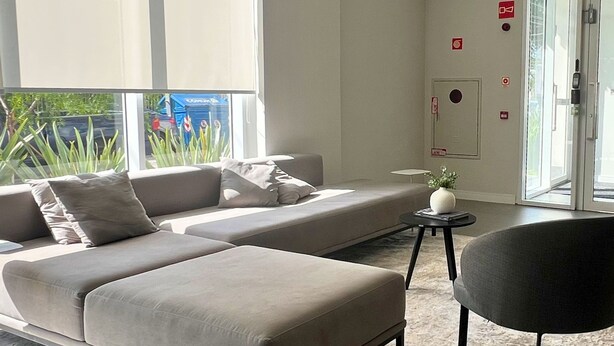 Una sala moderna con un sofá seccional, una mesita redonda con un florero y una silla.