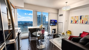 A modern living room with a dining area, a TV, and a city view. - Commerce Suites and Stays (Vaughan)
