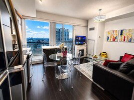 Una sala de estar moderna con comedor, televisor y vista a la ciudad.