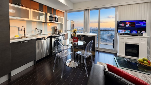 A modern kitchen with a dining area, large windows, and a flat-screen TV. - Commerce Suites and Stays (Vaughan)