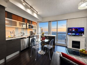 A modern kitchen with a dining area, large windows, and a flat-screen TV. - Commerce Suites and Stays (Vaughan)