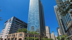 A tall, modern skyscraper with reflective glass windows, surrounded by other high-rise buildings. - Commerce Suites and Stays (Vaughan)