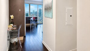 A modern interior with a view of a cityscape, a dining area with clear chairs, and a white door. - Commerce Suites and Stays (Vaughan)