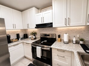 A modern kitchen with white cabinets, stainless steel appliances, and a tiled backsplash. - La Casita Mall of Millenia Orlando (Orlando)