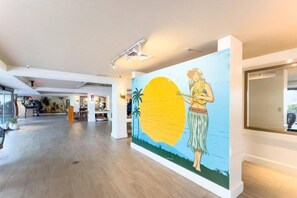 A hotel lobby with a large mural, a reception desk, and a modern interior design. - Modern Waikiki Studio | Hilton Lagoon+Free Parking (Honolulu)