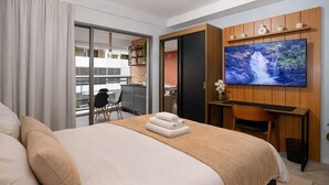 Habitación de hotel con cama, escritorio, televisor y vistas al exterior.