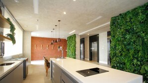 Una cocina moderna con una isla grande, electrodomésticos integrados y una pared vertical con jardín.