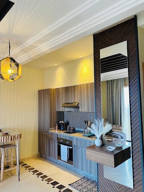 A modern kitchen with a built-in stove, a hanging light fixture, and a large mirror. - 2 bedroom apartment, private rooftop and swimming pool + aqua-park free access (Ouahat Sidi Brahim)