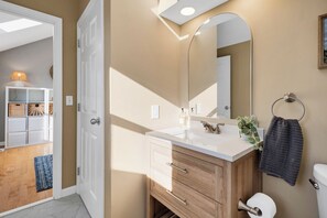 A bathroom with a white vanity, wooden cabinet, and a large mirror.
