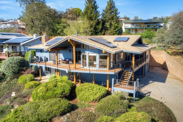 Une maison moderne dotée d’une grande terrasse, de panneaux solaires et d’un escalier menant à un étage supérieur.