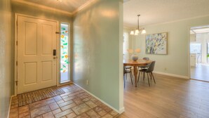Un couloir avec une porte, un coin repas avec une table et des chaises, et un luminaire.