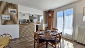 A dining area with a wooden table, chairs, and a view of the kitchen in the background. - Saint-Palais-sur-Mer – BRIGHT HOUSE – a relaxing escape between sea and nature (ST PALAIS SUR MER)