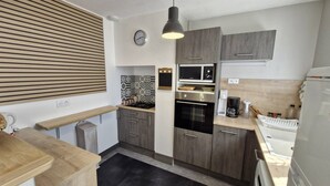 A compact kitchen with a built-in microwave, oven, and a coffee maker on the countertop. - Saint-Palais-sur-Mer – BRIGHT HOUSE – a relaxing escape between sea and nature (ST PALAIS SUR MER)