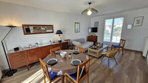 Ein modernes Wohnzimmer mit Essbereich, einer Couch, einem Fernseher und einem großen Fenster.