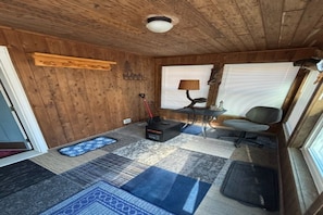 Ein Holzinterieur mit Deckenventilator, einem Tisch mit Lampe, einem Sessel und einem gemusterten Teppich.