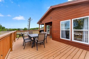 A wooden deck with a table and chairs, a covered patio area, and a large window.
