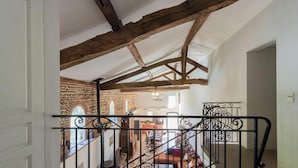A staircase with wrought iron railings leading to a room with exposed wooden beams and a brick wall. - Le Boucaou - SABONNERES (SABONNERES)