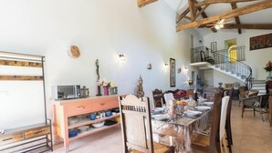A dining area with a wooden table set for a meal, a staircase, and a view of the upper floor. - Le Boucaou - SABONNERES (SABONNERES)