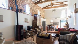 A living room with a fireplace, wooden furniture, and a brick wall. - Le Boucaou - SABONNERES (SABONNERES)