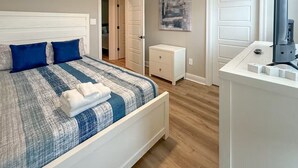 Een slaapkamer met een bed, een dressoir, een deur en een koffiezetapparaat.
