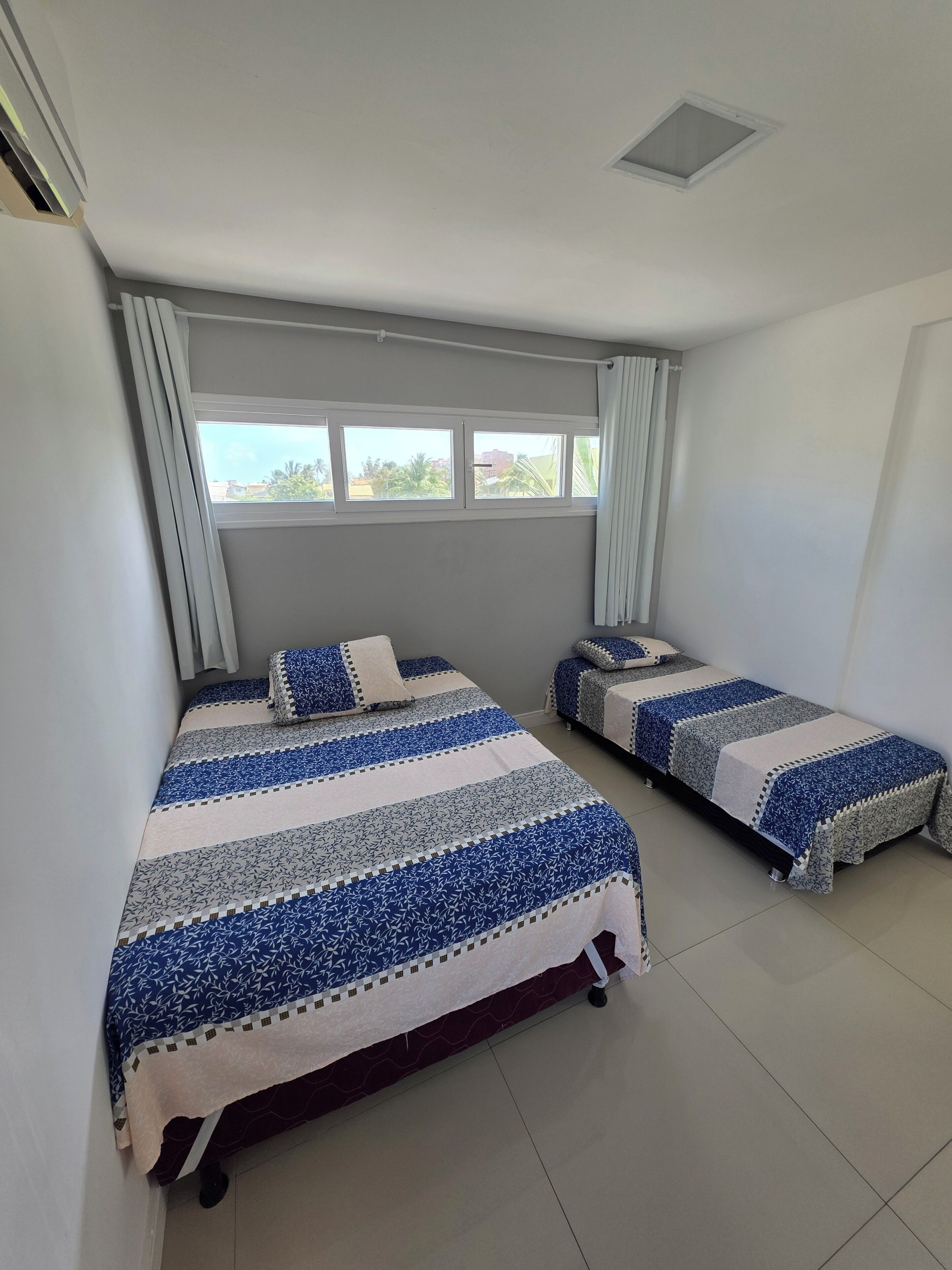 Una habitación con dos camas, una ventana y un respiradero en el techo.