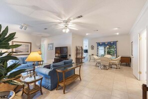 A living room with a sofa, TV, and a dining area with chairs.