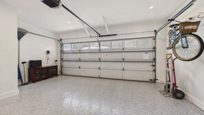 A garage with a closed garage door, a bicycle mounted on a wall, and a lift for the bicycle.