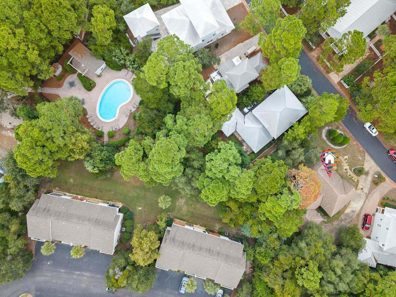 An aerial view of a residential area with houses, a swimming pool, and a road.
