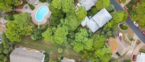 An aerial view of a residential area with houses, a swimming pool, and a road.