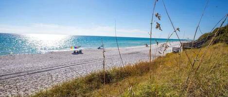 A beach with a clear sky, a sandy shore, and a few boats.