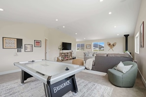 A modern living room with a pool table, a sofa, and a green armchair.