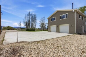 A two-story house with a garage, a driveway, and a gravel area.