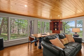 A spacious room with a wooden ceiling, large windows, a black leather sofa, a wooden dining table, and a bookshelf. - Come relax at your home away from home walking distance to downtown Boulder! (Boulder Junction)
