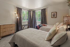 Quarto com duas camas, um radiador, uma mesa pequena e um abajur.