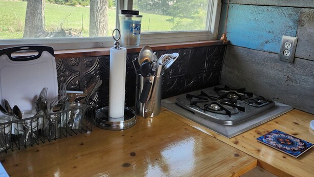 A kitchen with a window, a stove, and utensils. - Tiny House on Century Farmstead (Muskego)