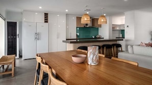Une cuisine moderne avec des meubles blancs, une table à manger en bois et un îlot central vert.