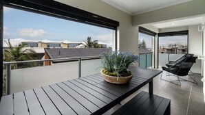 Un balcon avec une table, un pot de fleurs et une chaise.