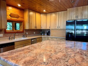 A modern kitchen with wooden cabinets, a granite countertop, and stainless steel appliances. - Maxwell Reserve • Private Forest Retreat • Sleeps 14 (Tionesta)