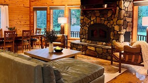 A cozy cabin interior with a stone fireplace, wooden walls, a flat-screen TV, and a dining area. - Maxwell Reserve • Private Forest Retreat • Sleeps 14 (Tionesta)